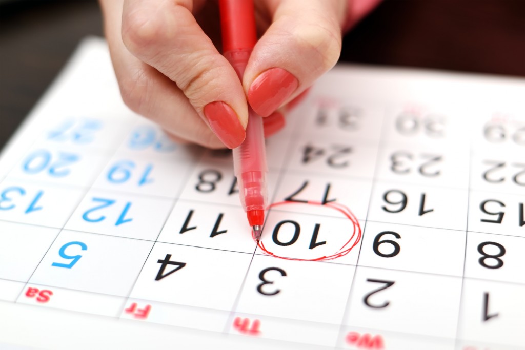 close-up of woman highlighting date on calendar