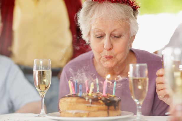 Senior-woman-blowing-out-candles-at-birthday-party